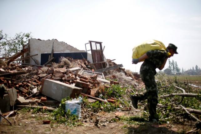 A paramilitary policeman carries a bag of medicine outside a damaged house after a tornado hit Funing on Thursday, in Yancheng, Jiangsu province, June 25, 2016. REUTERS/Aly Song