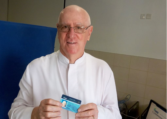 Father Campbell showing off his NHIS card after registering onto the Scheme on Tuesday.