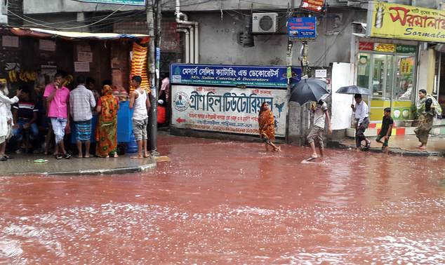 In this Tuesday, Sept. 13, 2016 photo, people wade past a road turned red after blood from sacrificial animals on Eid al-Adha mixed with water from heavy rainfall in Dhaka, Bangladesh. Authorities in Dhaka had assigned several places in the city where residents could slaughter animals, but the heavy downpours Tuesday meant few people could use the designated areas. (AP Photo)