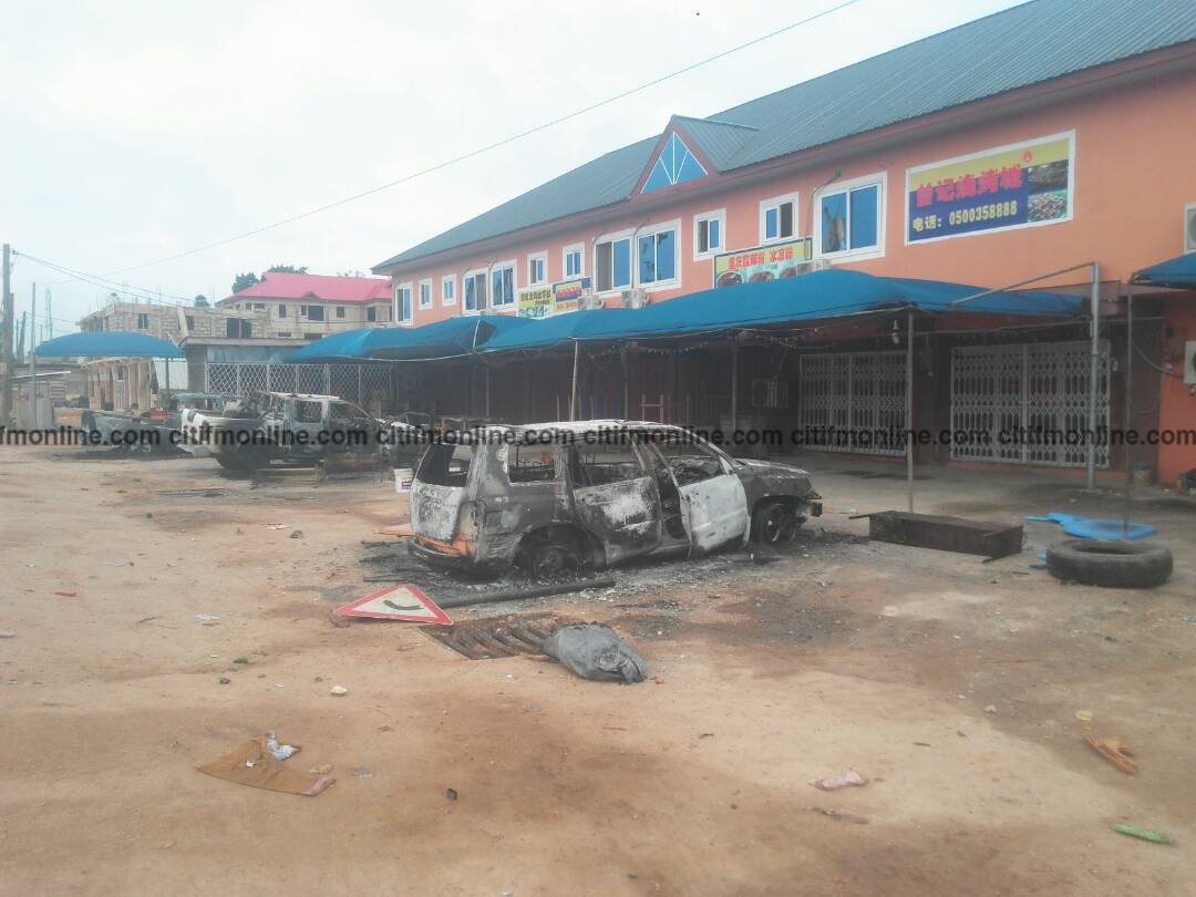 Some burnt cars in front of a Chinese company