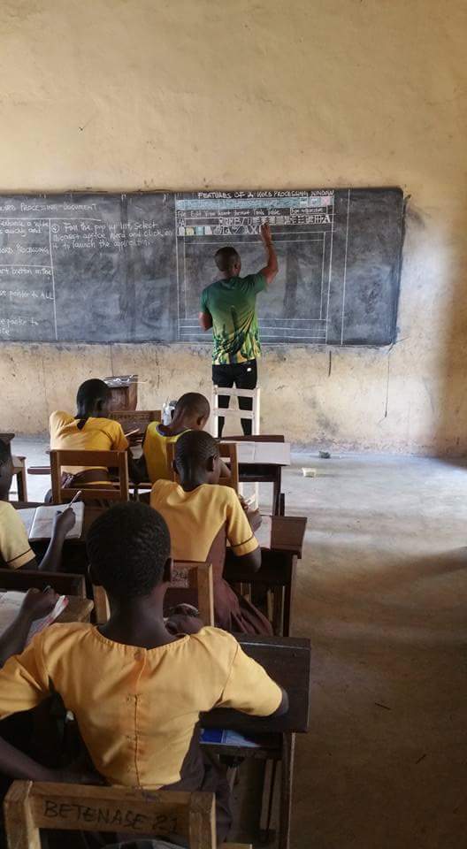 Students write in their notebooks as Owura Kojo sketches on the board